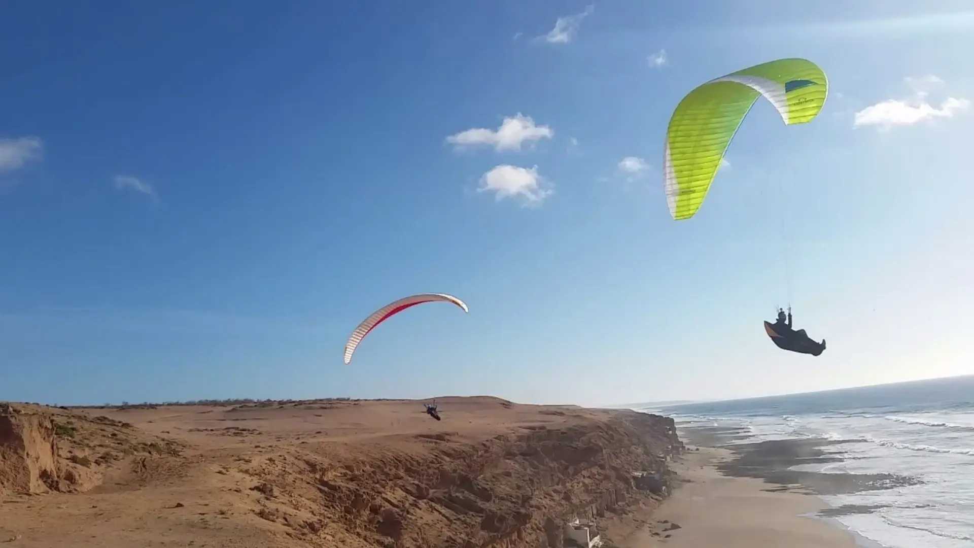 Paraglider flying above a wide Atlantic beach in Morocco